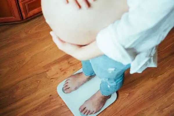 Image of woman weighing herself and experiencing weight gain through pregnancy Hampton in Arden